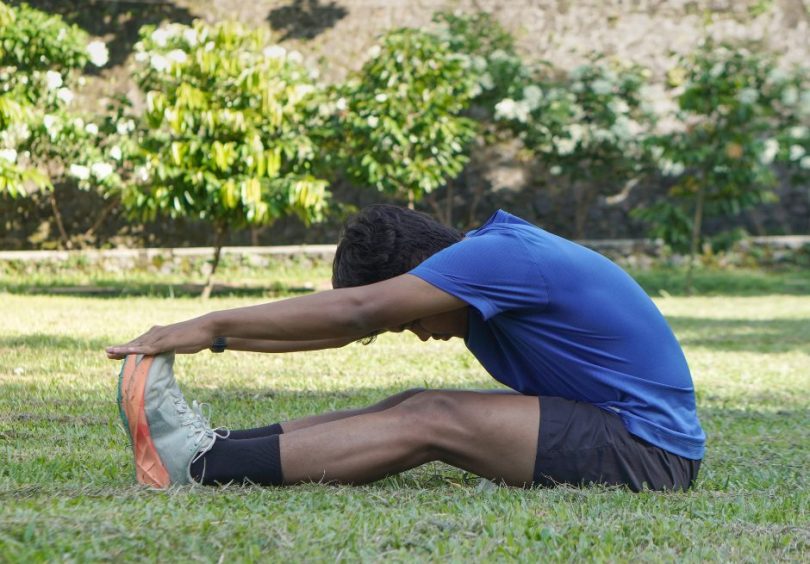 Footballer performing a seated hamstring stretch to improve flexibility as part of a hamstring injury prevention and rehabilitation programme.